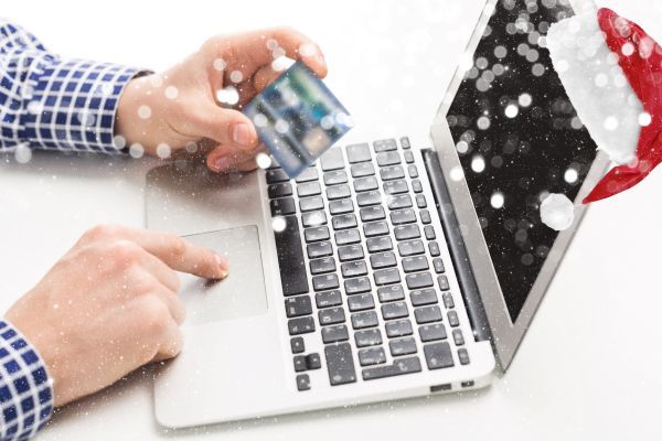 Someone using a computer using their card to make a purchase for the holidays.