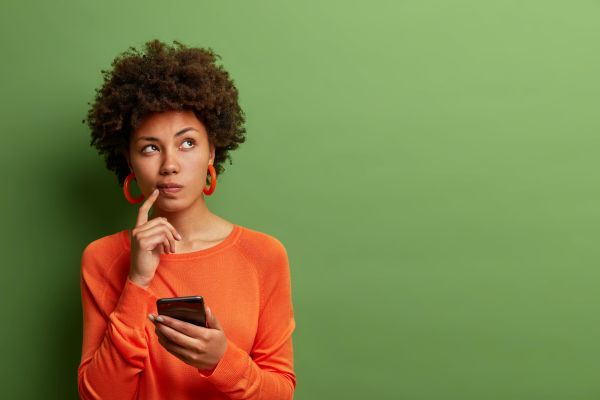 Woman thinking as she browses through her phone