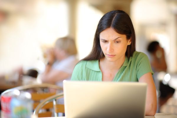 Woman at a restaurant looking suspiciously at her laptop