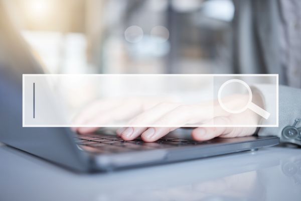 A Search bar with a person behind typing on a computer