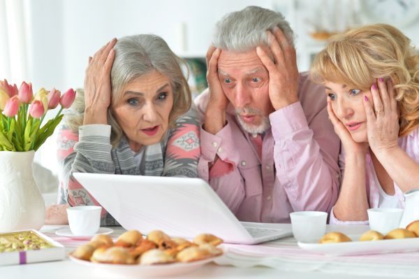 Three shocked people staring at a laptop